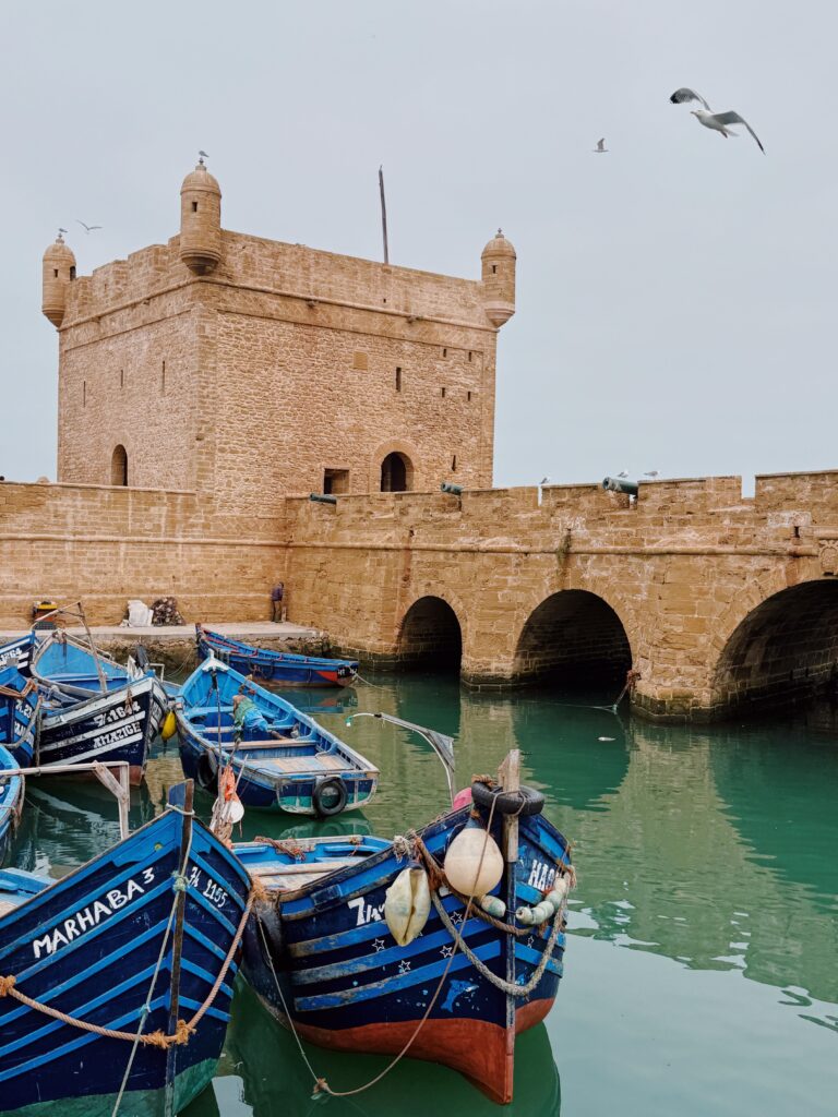 Classic stone fortress overlooking vibrant blue fishing boats in Essaouira's historic port.