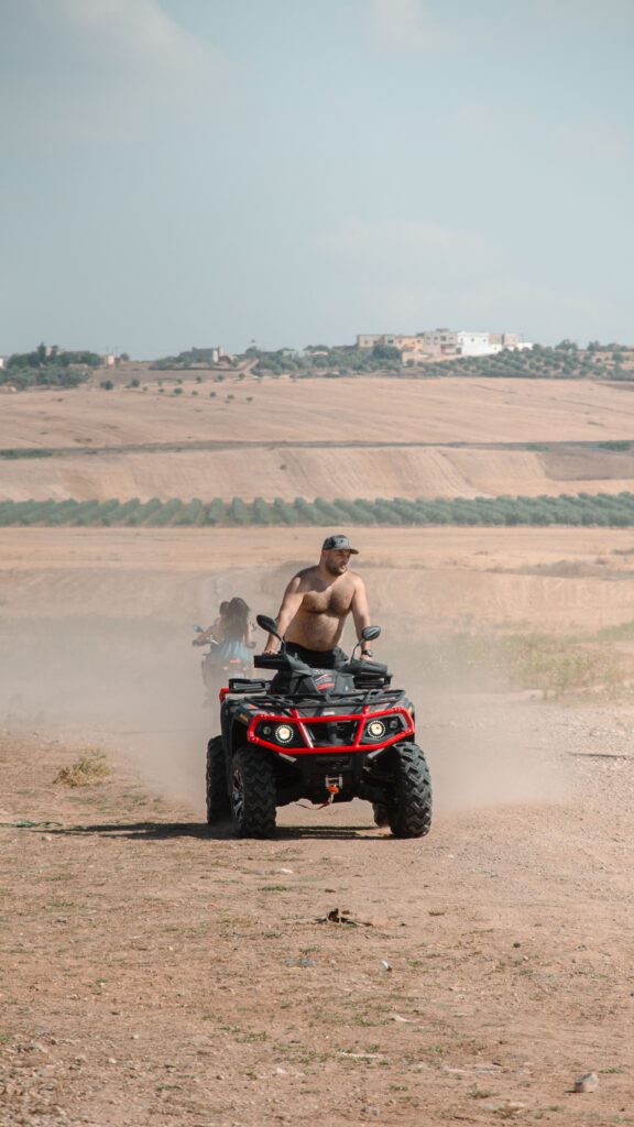 Man riding ATV through the dusty Moroccan desert under clear skies